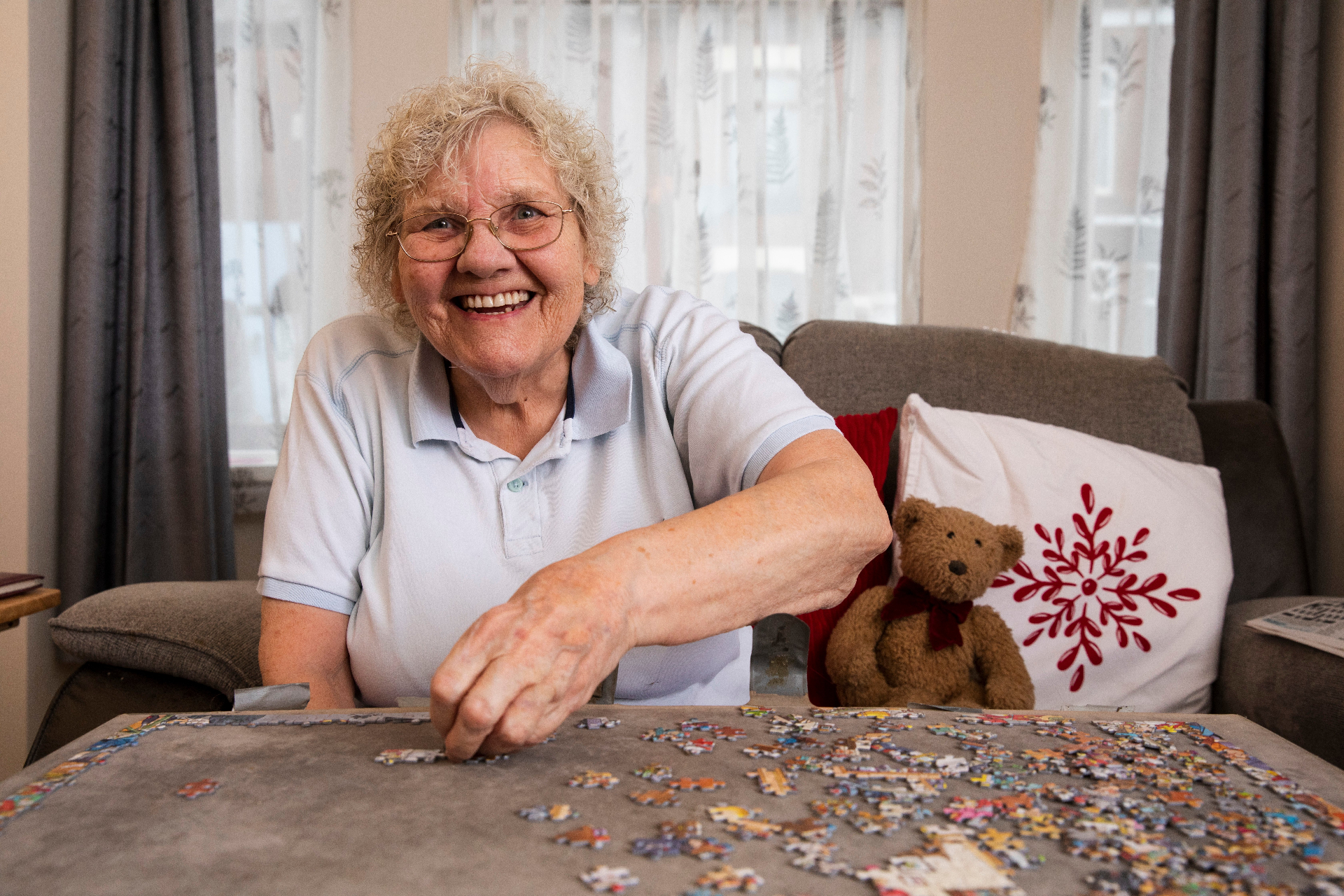 Older woman smiling while doing a jigsaw puzzle