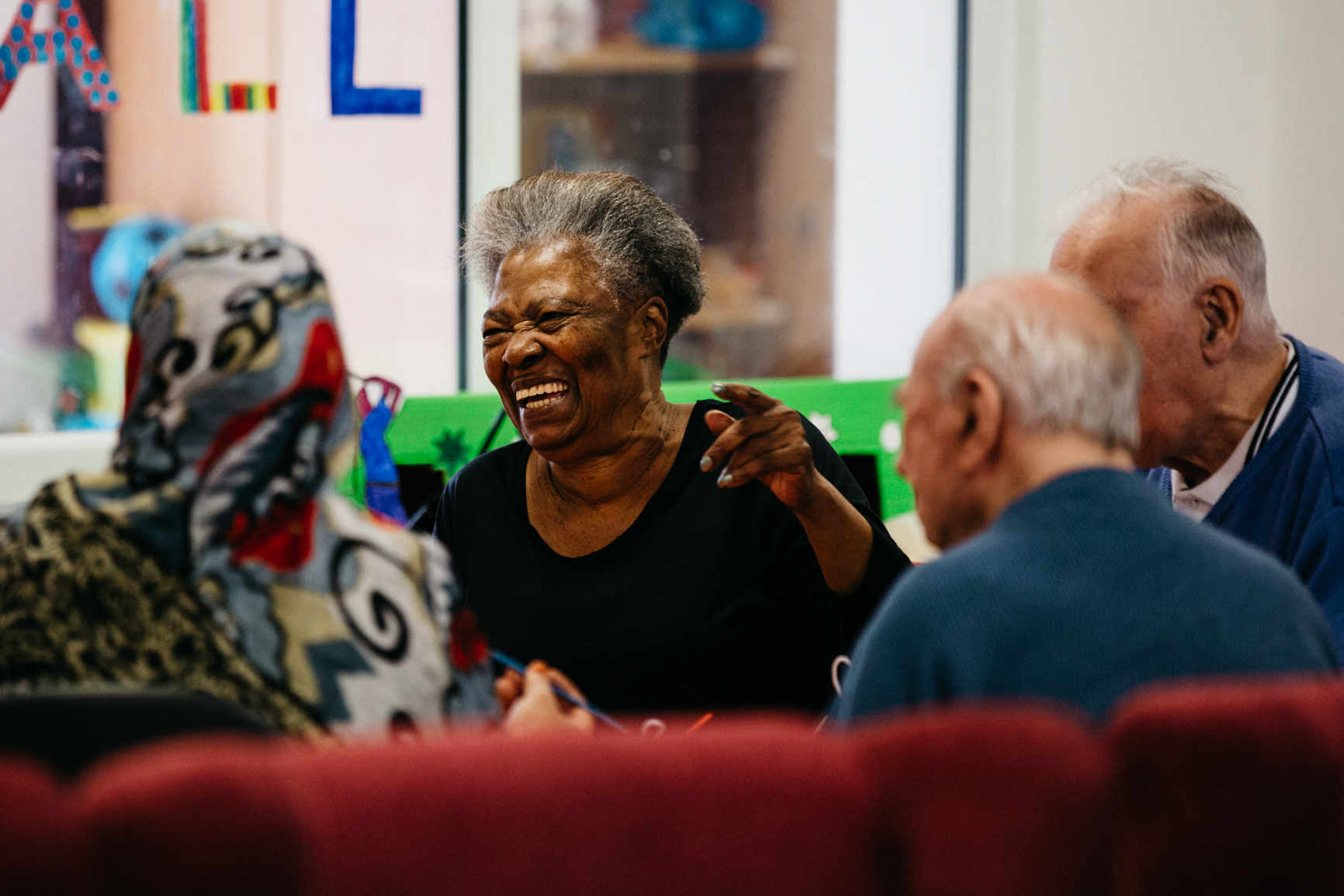 Older woman laughing with friends at a community centre